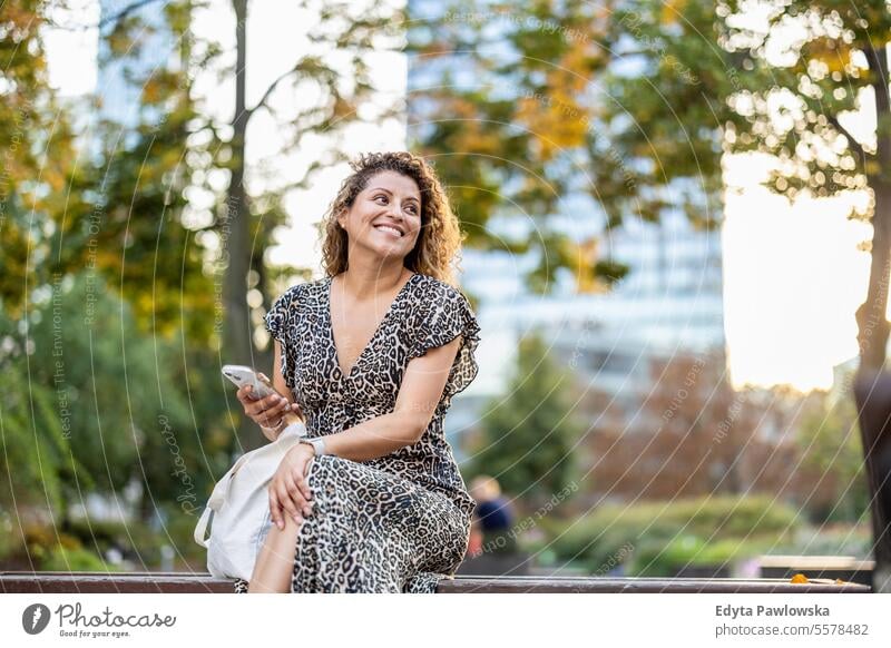 Portrait of a smiling young woman using mobile phone in the city young adult street outside confidence enjoy laughing fun natural one person portrait expression