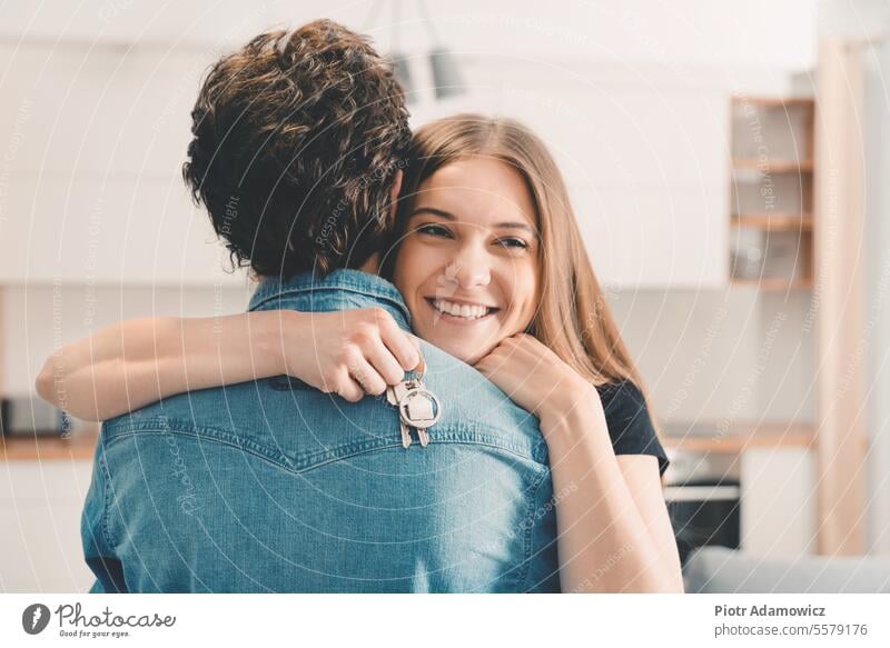 New home owners with keys, happy woman hugs new house family couple apartment young interior people lifestyle enjoying holding hugging pendant ring attractive