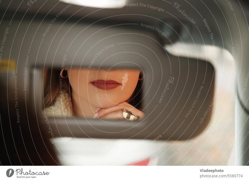 Woman lips in vanity mirror while sitting in car. female woman beautiful makeup attractive driver beauty young automobile lipstick vehicle caucasian traffic