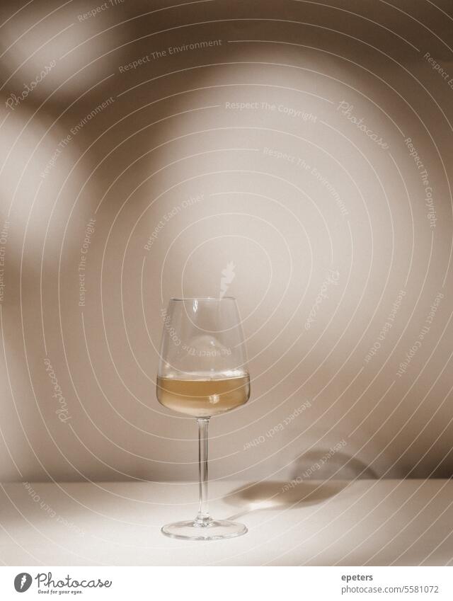Glass of white wine on a beige background with spots of light Fine dining luxury culinary drink Alcoholic beverage glassware aesthetics Chilled elegance