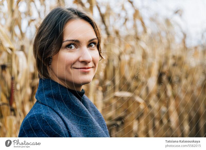 Portrait of attractive young woman in autumn coat in cornfield portrait rows fall outdoors rural countryside harvest seasonal agricultural farming nature