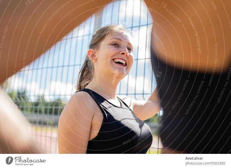 Girl leaning on a fence on athletics track talking to other girls.Healthy hobby to do with friends. sport female women fitness healthy exercise adult lifestyle