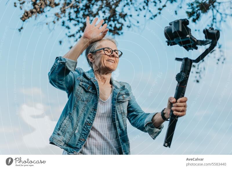 Senior joyful woman recording a video for her family explaining her vacation. Old photographer. retirement adult person streamer live lifestyle senior outdoors