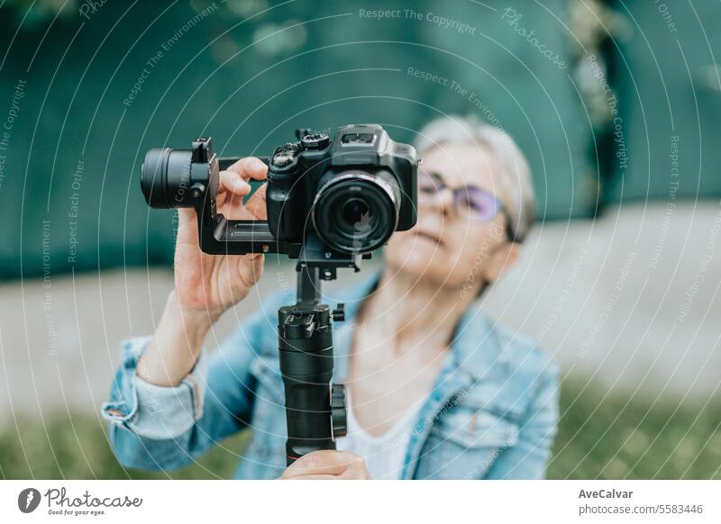 Concentrated senior woman arranging and preparing to record with her camera, photos and videos. retirement streamer live person female young lifestyle beauty