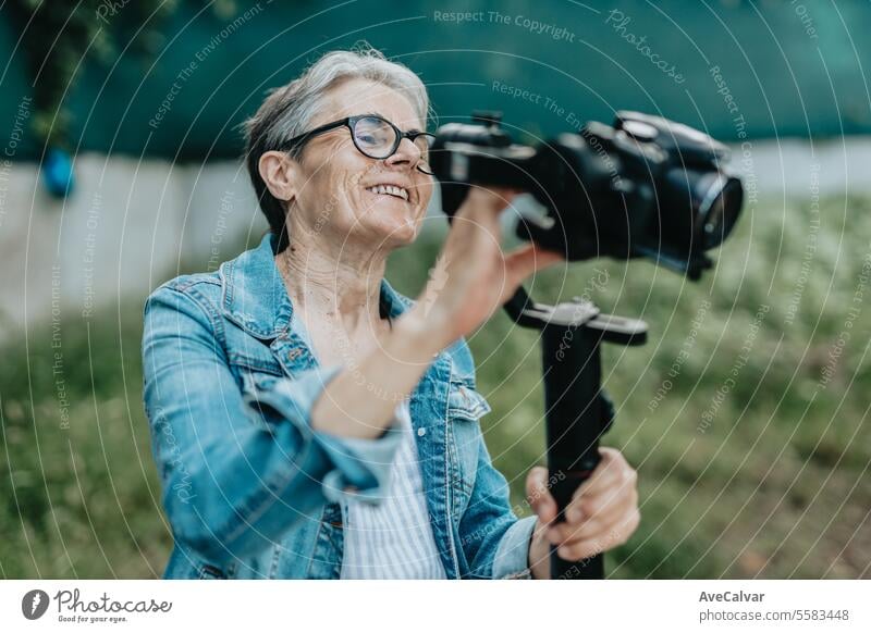 Concentrated senior woman arranging and preparing to record with her camera, photos and videos. retirement women female adult person lifestyle caucasian
