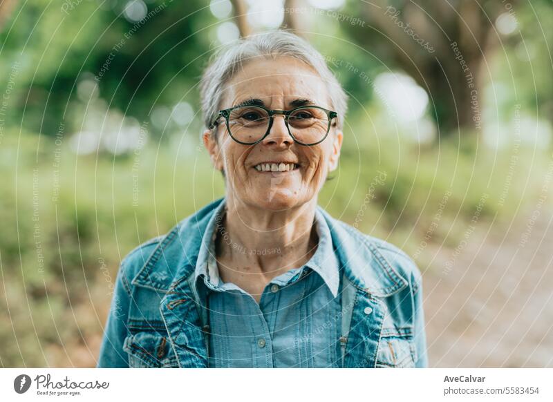 Portrait of older lady enjoying nature in forest, taking a walk breathing fresh air outside the city mental retirement elderly happy senior person woman