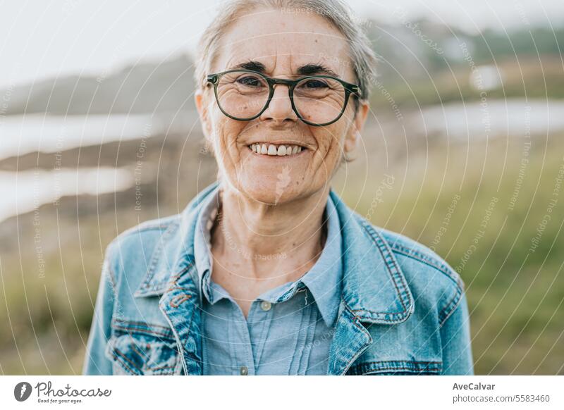 Smiling adult woman with short gray hair visiting a beach, connecting with nature taking a walk. mental health retirement old senior retired person women smile