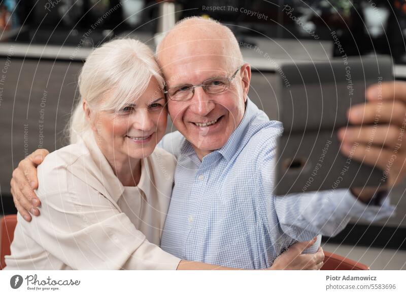 Cheerful senior couple taking selfie phone cell indoors mobile camera fun happy carefree grandfather domestic kitchen cheerful comfortable contemporary cosy