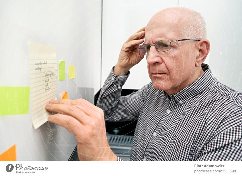 Elderly man with dementia looking at notes memory loss person elderly confused senior old mature remember amnesia problems pondering list sticky care aging