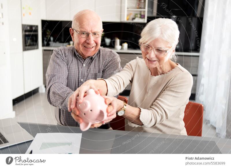 Senior couple is trying to get the savings senior money piggybank aged funny caucasian coin shake bill family female finance home pension plan income insurance