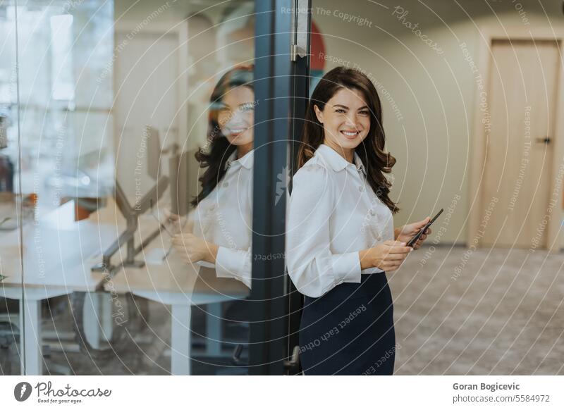 Young woman with digital tablet standing in the modern office young businesswoman female attractive technology portrait wireless occupation confident