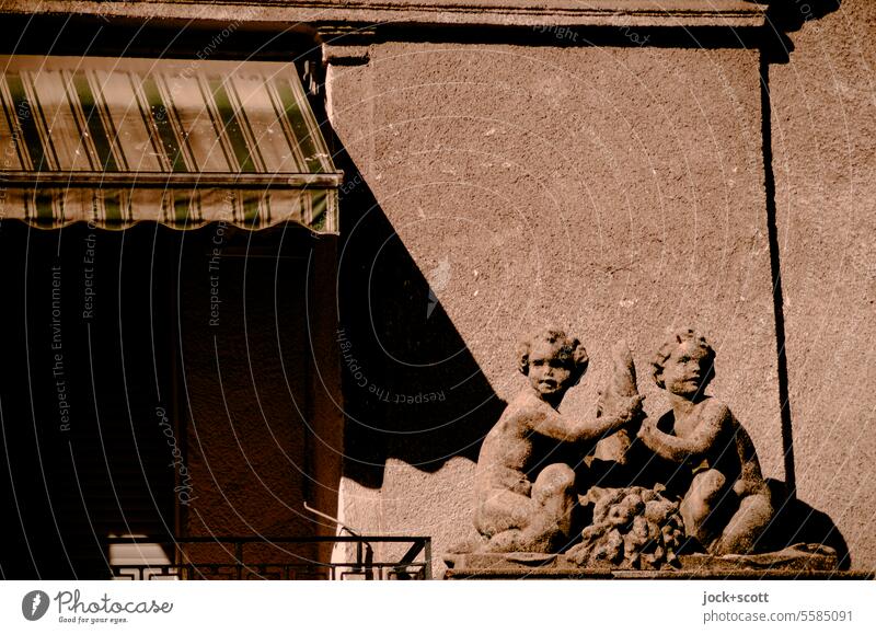 Putti with flower horn as decoration on facade cornucopia Facade Decoration Sun blind Shadow Sunlight Neutral Background Style Retro Weathered Silhouette