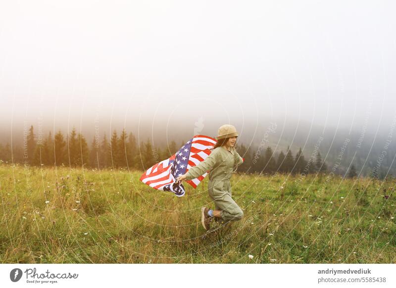 Beautiful child girl in hat with the American flag on foggy mountains. Independence Day of United States USA on 4th of July with family. Freedom. American patriotic holiday concept