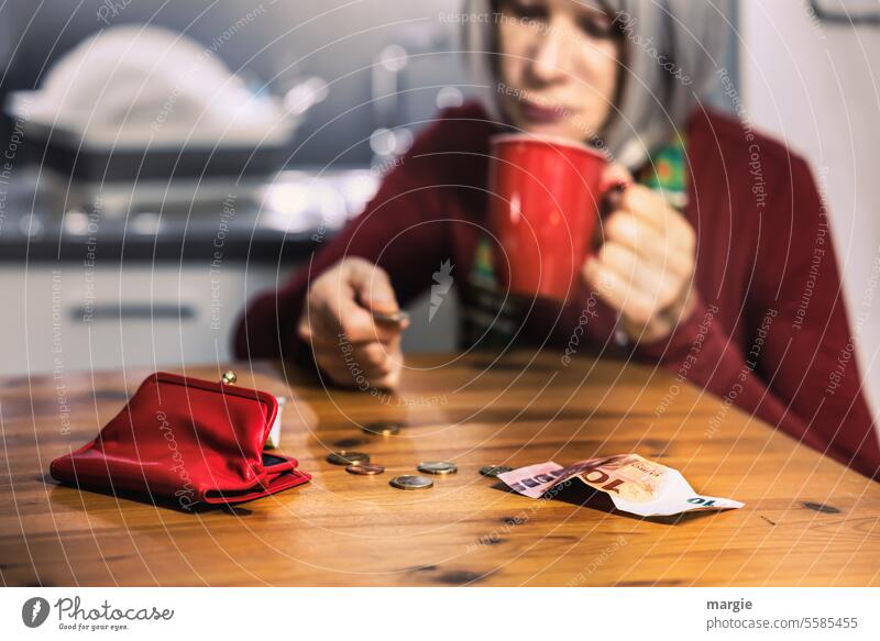 A sad woman in the kitchen counts her household money Woman Kitchen Money Numbers Coin Bank note Loose change Hand Poverty Cup Euro Save Wallet Red Table