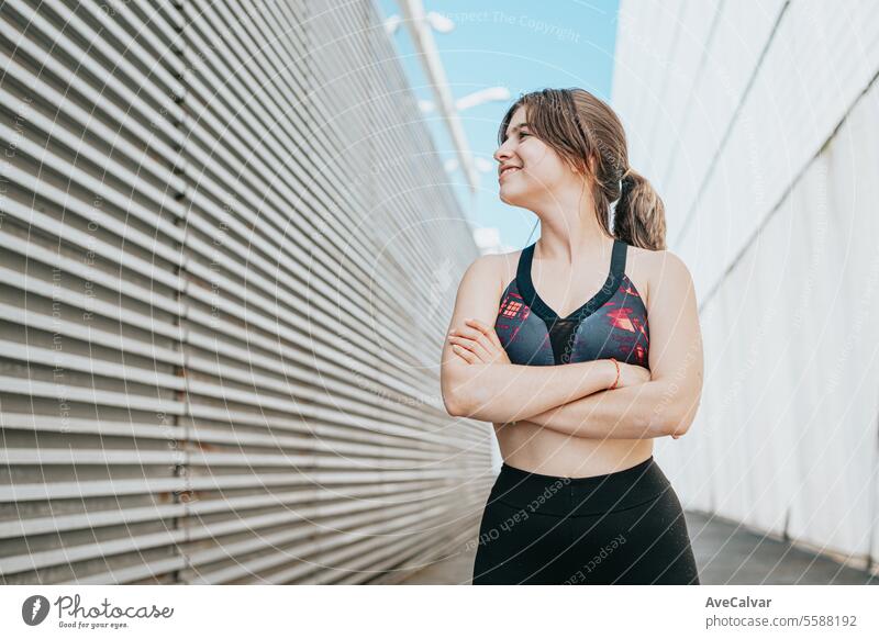 Portrait of a sporty, athletic and exercised smiling woman with her arms crossed in a street setting female sports fitness lifestyle person young healthy adult