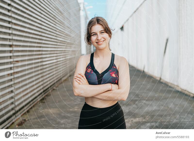 Happy jovial healthy young woman posing between building in urban environment with sporty atmosphere women female lifestyle fitness exercise person athletic