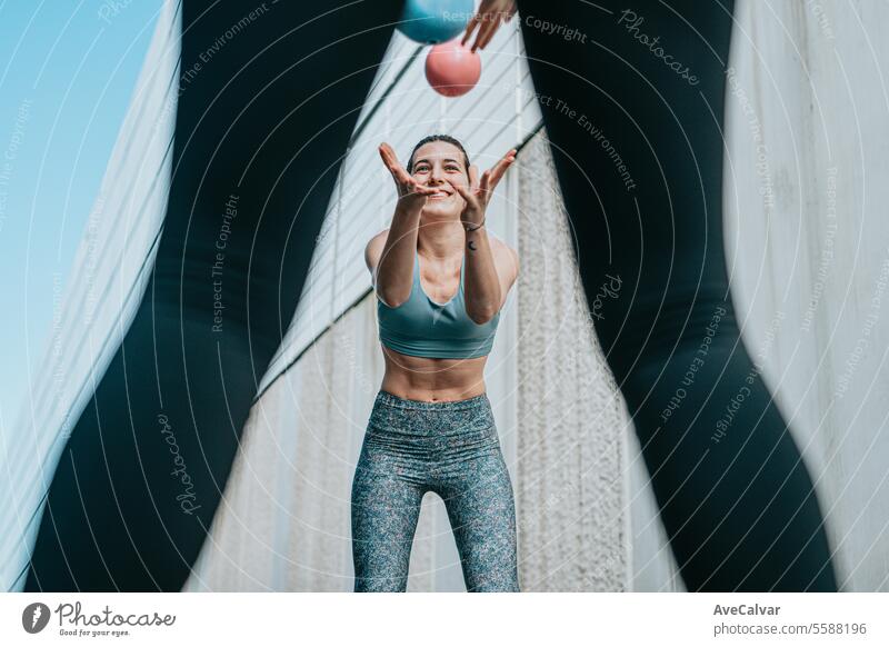 Smiling athletic girl doing series of exercises with a medicine ball on training day. Urban scene. sport female fitness woman person young active outdoor urban