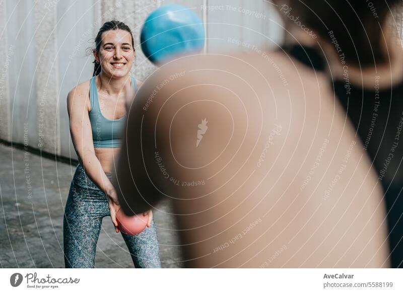 Two fit women doing sports together, using a medicine ball to tone their body. Urban scene. woman female fitness training exercise gym outdoor urban friends