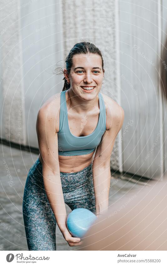 Smiling athletic girl doing series of exercises with a medicine ball on training day. Urban scene. fitness healthy women lifestyle sport female outdoor urban