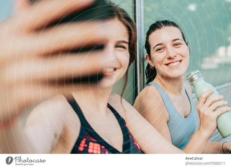 Couple of happy friends after having finished training for their favorite sport, taking some selfies with cell phone. person female young lifestyle women beauty