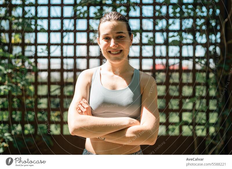 Portrait of a smiling girl in sportswear on a wooden background with green leaves.Sport in the city. female women young beauty person lifestyle healthy fitness