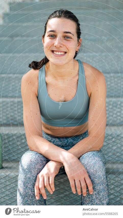 Portrait of a smiley female personal fit trainer looking at camera in an urban street setting. sport athletic women lifestyle fitness healthy sporty training