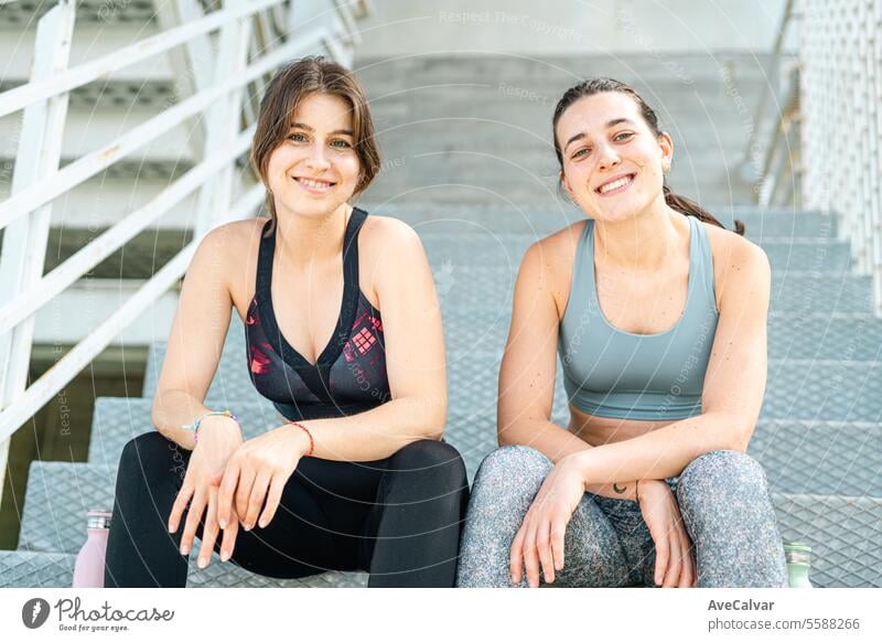 Portrait of two smiley female personal fit trainer looking at camera in an urban street setting. lifestyle fitness sport exercise training young outdoor friends