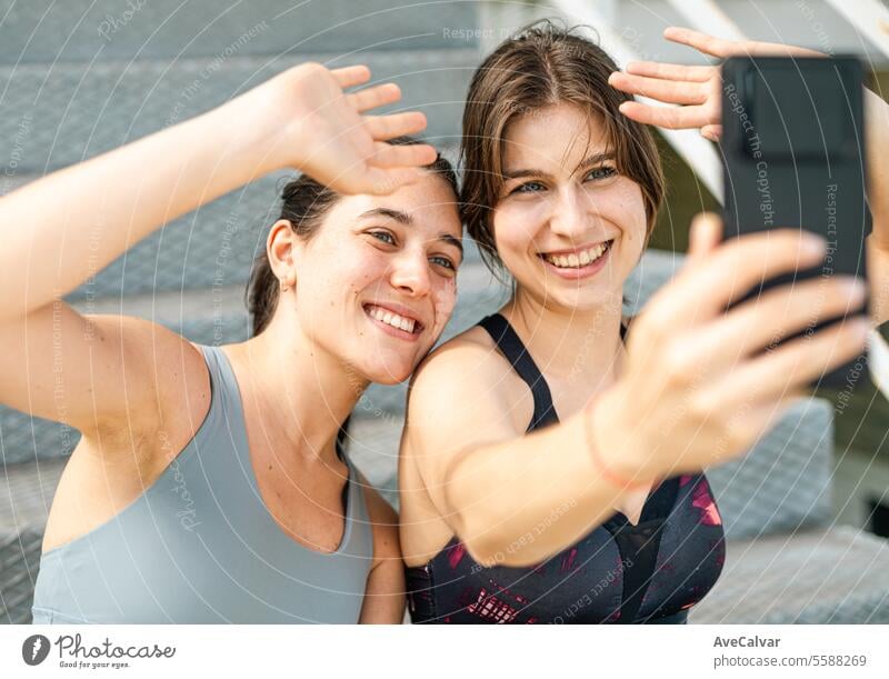 Couple of happy friends after having finished training for their favorite sport, taking some selfies with cell phone. female young person women lifestyle two