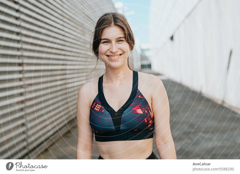 Portrait of a smiley female personal fit trainer looking at camera in an urban street setting. women sport beauty young fitness exercise lifestyle healthy
