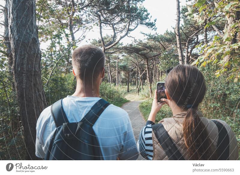 travelling couple captures their discoveries on their mobile phone. A park near Blankenberge. Wild nature.  Experiencing things together dating romantic