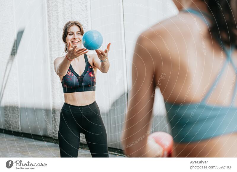 Two fit women doing sports together, using a medicine ball to tone their body. Urban scene. fitness outdoor urban friends training exercising gym athletic woman