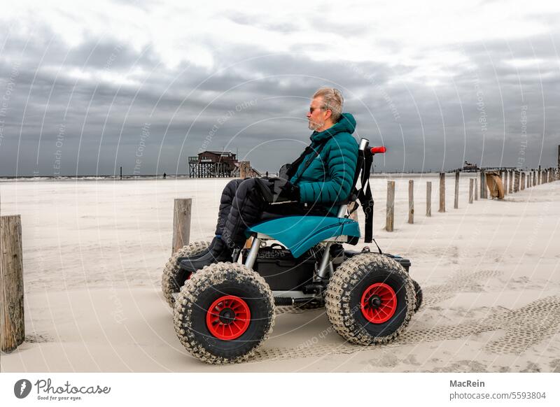 Man in a beach wheelchair, enjoying a beach vacation Adventure activity on one's own Exterior shot handicapped Disabled Energy Relaxation more adult holidays