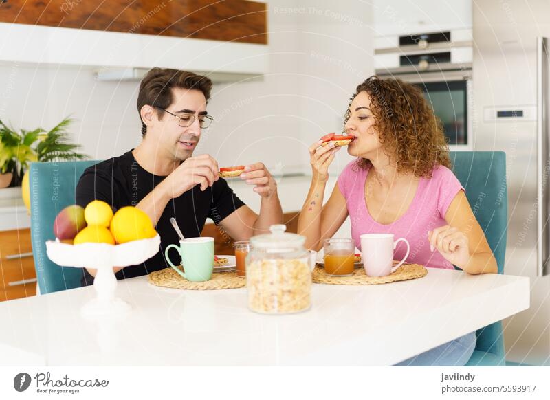 Happy adult couple sitting at dining table and speaking during breakfast happy eat salad healthy food smile communicate conversation male eyeglasses female