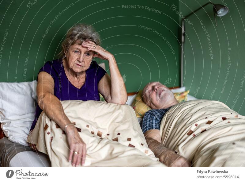 Senior woman can't sleep because her husband is snoring real people senior mature female couple together Caucasian elderly home house old aging domestic life