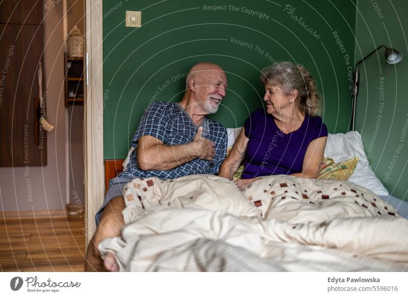 Elderly couple sitting in bed and looking at each other with love bedroom morning bonding beloved happy talking smiling joy enjoying affection romance closeness