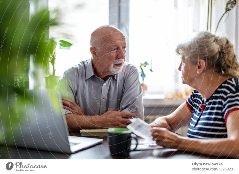 Senior couple discussing their home finances while sitting at the table real people woman senior mature female together Caucasian elderly house old aging