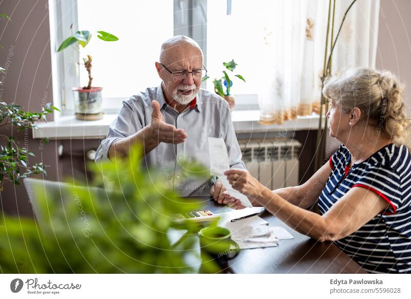 Senior couple discussing their home finances while sitting at the table real people woman senior mature female together Caucasian elderly house old aging