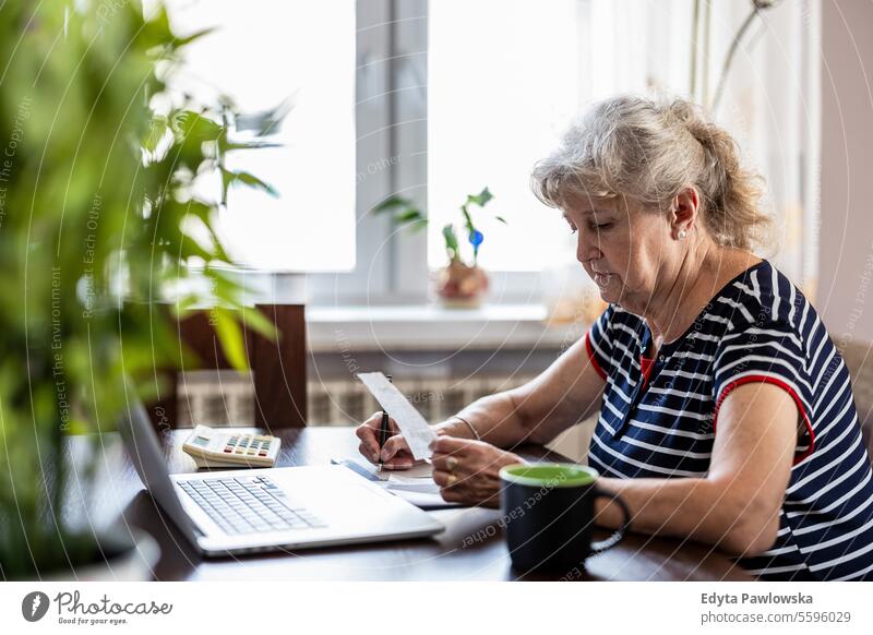Senior woman going over her finances at home real people senior mature female Caucasian elderly house old aging domestic life grandmother pensioner grandparent