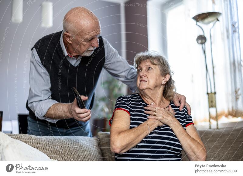 Senior woman suffering from chest pain while her husband comforting her real people senior mature female couple together Caucasian elderly home house old aging