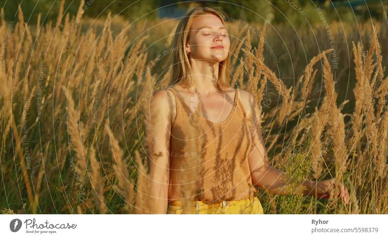 Portrait Of Young Pretty Caucasian Happy Girl Woman Use Breathing Programs At Summer Meadow. Healthy Lifestyle Concept. Unity With Nature. Yoga Concept Lifestyle. Calmness And Tranquility