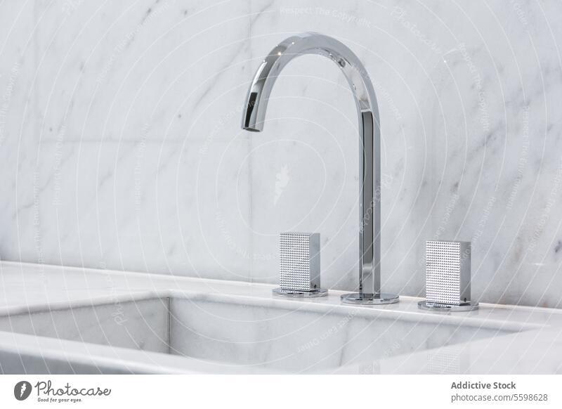 Steel faucet with knobs at kitchen sink penthouse closeup metal marble tile wall modern style trendy home interior residential dwell real estate property