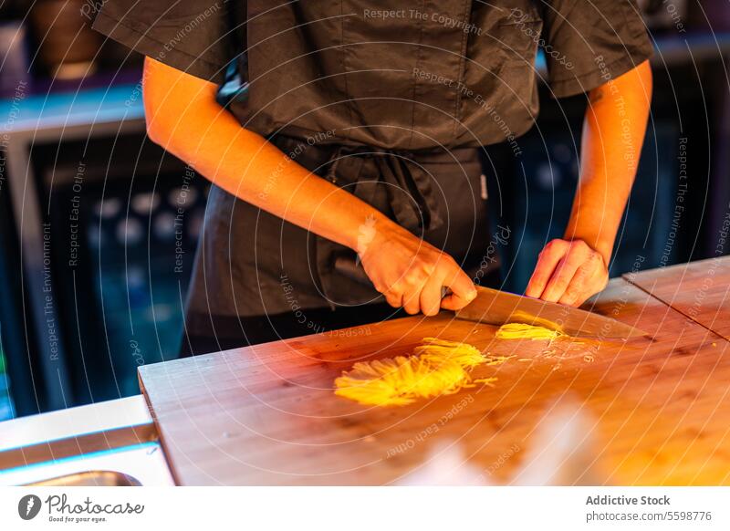 Skilled crop anonymous cook in black uniform standing at counter while cutting and preparing meal at sushi bar woman chef knife slicing carrot nightclub