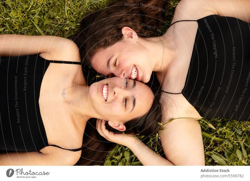 Happy women lying on the grass in a moment of affection woman laughter LGBT pride lesbian couple connection love outdoors happiness intimacy bond smile