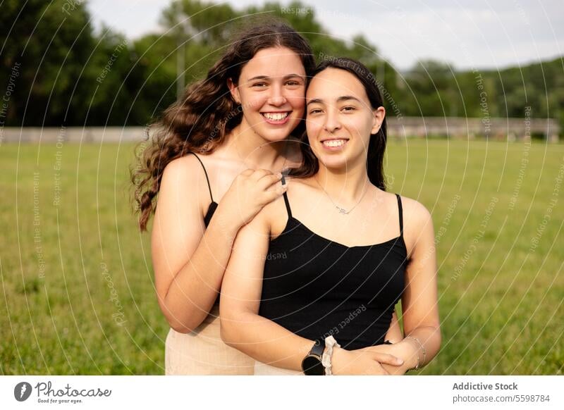 Happy young women looking at the camera in nature woman smile embrace casual field love LGBT pride lesbian couple green outdoors happiness joy affection summer