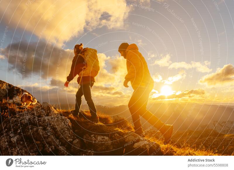hiking in the mountains at sunset man woman couple hike trekking sport exercise fitness walk adult young caucasian sunrise journey dog exploration together