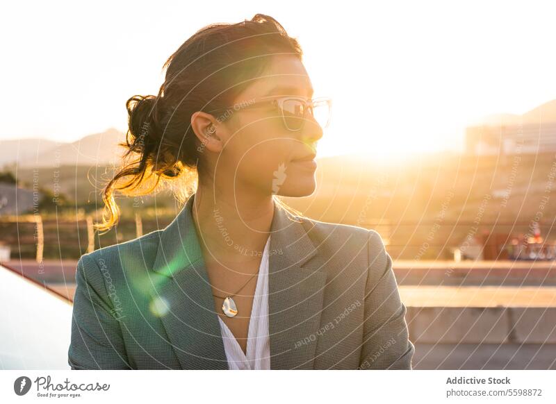 Stylish entrepreneur looking away in city woman sunglasses backlit young businesswoman blazer blur background female professional urban lady think beautiful