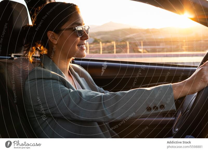 Happy businesswoman in sunglasses driving car executive portrait smiling beautiful young driver seat dashboard steering wheel happy entrepreneur