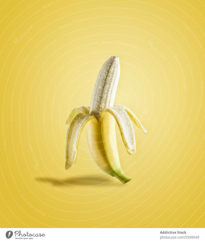 Half peeled banana in sunlight on yellow background. Delicious tropical fruit. Front view. half delicious front view food fresh half peeled healthy isolated