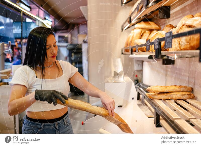 Young sales clerk putting bread in a bag portrait latina woman assistant customer store business entrepreneur food cafe service bakery occupation owner cheerful