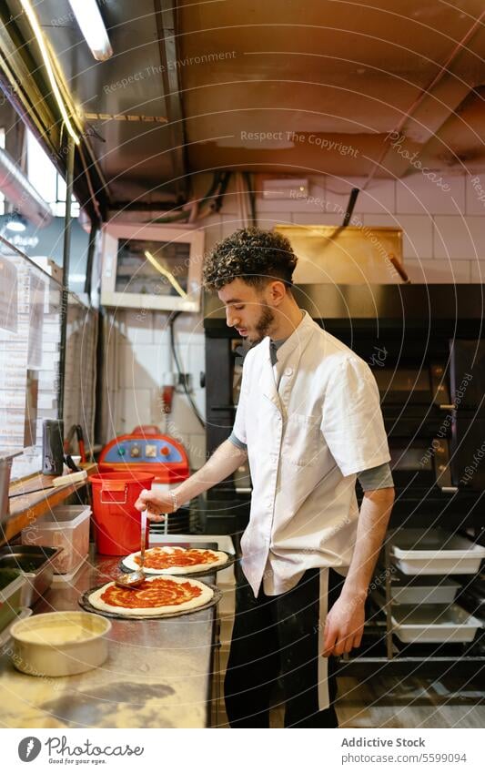 Pizza man making pizza in the kitchen of a pizzeria arabic food restaurant tomato sauce preparing italian cooking baker person meal preparation cuisine dough